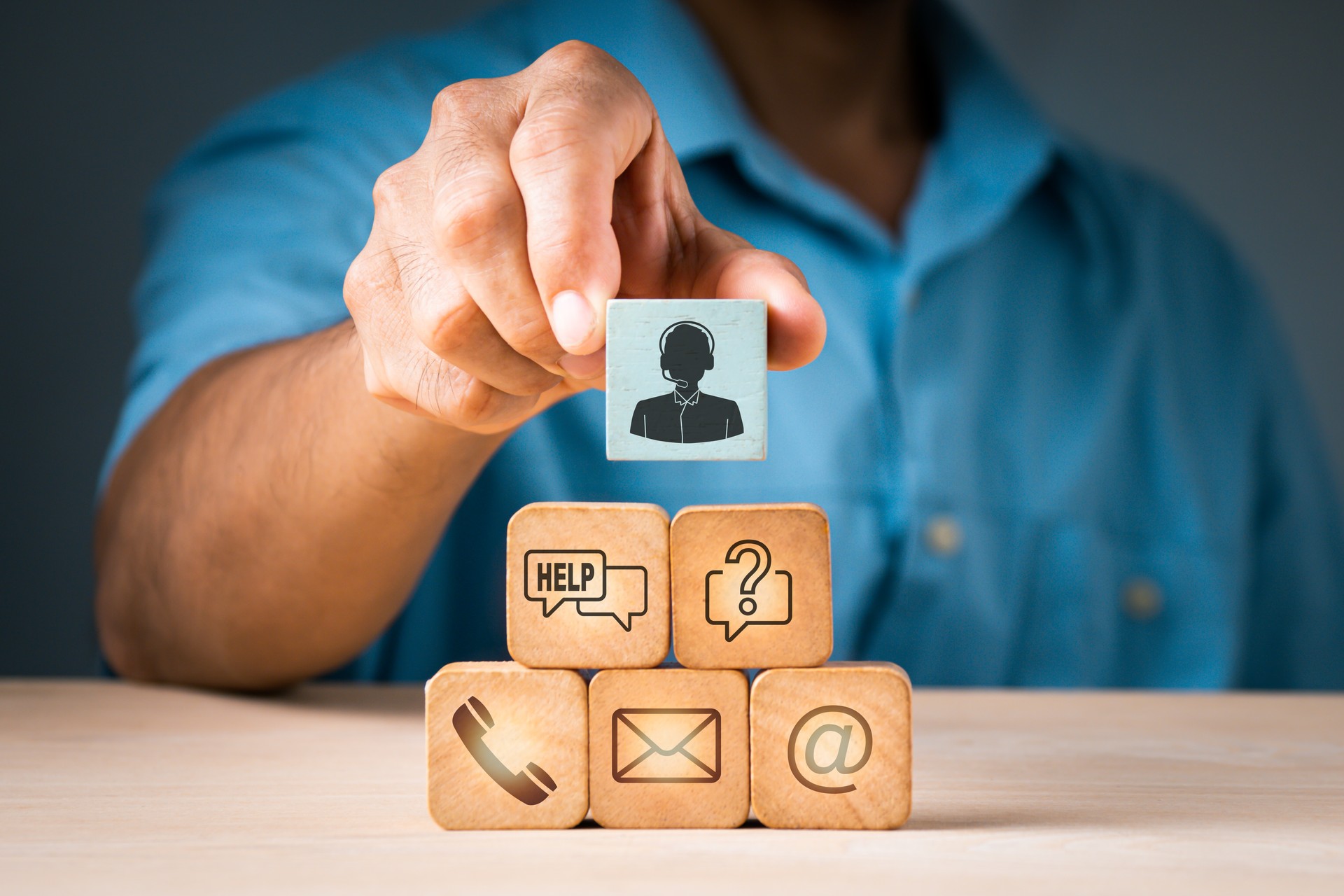 A businessman picks up a wood block with a symbol for an operator and icons for after-sales services. Customer satisfaction communication channel